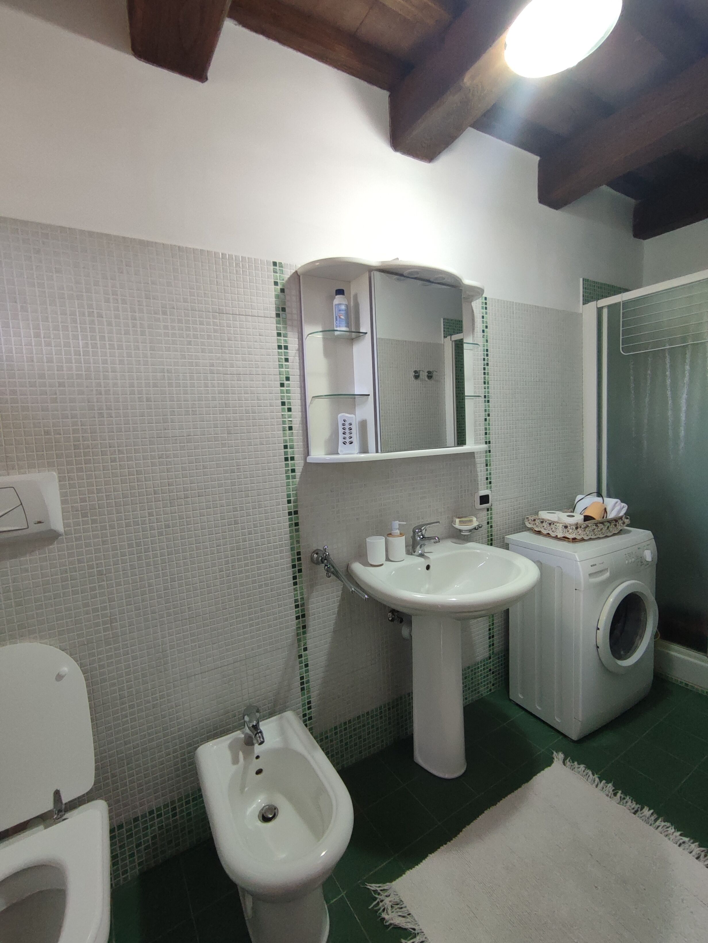 Une salle de bain équipée de toilettes, d’un bidet, d’un lavabo, d’un miroir et d’un lave-linge.