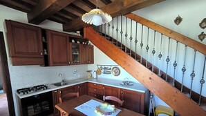 Una cocina con armarios de madera, una estufa a gas, un fregadero y un comedor con mesa y sillas.