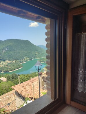 A view through a window with a view of a river, green hills, and a lamp post.