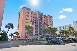 A multi-story hotel with a central atrium, outdoor parking, and palm trees. - Four Seasons 804E by Liquid Life (Orange Beach)