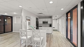 Una cocina moderna con armarios blancos, una isla central con asientos y un microondas sobre el fregadero.