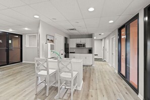 A modern kitchen with white cabinetry, a central island with seating, and a microwave above the sink. - Four Seasons 804E by Liquid Life (Orange Beach)