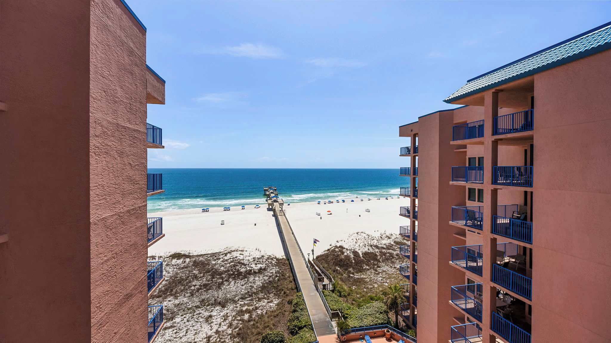 A beach view from a high-rise building with balconies, a sandy beach, and the ocean.