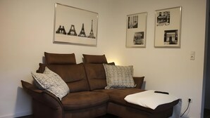 A brown sectional sofa with patterned pillows, a remote control, and a white throw blanket.
