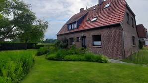 A brick house with a red roof, a small garden, and a hedge.