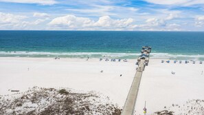 A beach with a concrete walkway leading to the water, beach umbrellas, and a clear view of the ocean. - Four Seasons 901W by Liquid Life (Orange Beach)