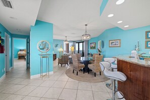 A spacious kitchen with a dining area, featuring a round table and chairs, a bar counter, and a chandelier. - Four Seasons 901W by Liquid Life (Orange Beach)