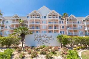 Ein mehrstöckiges Hotel mit Balkonen, einem Schild mit der Aufschrift 'The Grand Beach Resort' und angelegten Gärten.