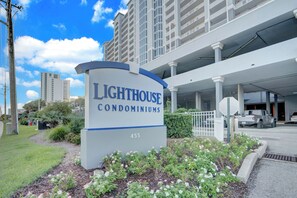 A sign for Lighthouse Condominiums with a clear view of the building's entrance and surrounding greenery. - Lighthouse 1505 by Liquid Life (Gulf Shores)