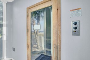A room with a wooden door leading to a balcony, a thermostat, and a warning sign about overheating. - Lighthouse 1505 by Liquid Life (Gulf Shores)