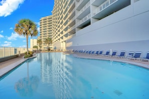 A swimming pool with lounge chairs, a palm tree, and a tall building in the background. - Lighthouse 404 by Liquid Life (Gulf Shores)