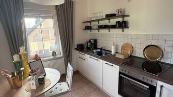 Eine moderne Küche mit weißen Schränken, einem eingebauten Backofen und einem Essbereich mit Tisch und Stühlen.