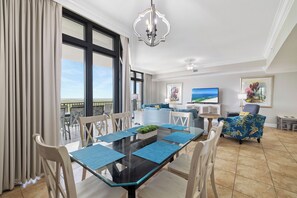 A modern living room with a dining area, large windows, and a view of the ocean. - The Oasis at Orange Beach 2013 by Liquid Life (Orange Beach)