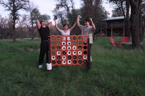 A group of people standing in a grassy area with trees and a building in the background.