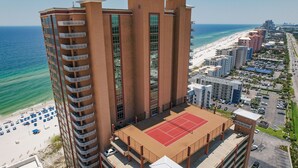 Een hoog hotel met meerdere balkons met uitzicht op een strand en de oceaan.