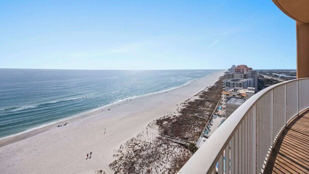 Uitzicht op het strand vanaf een balkon, met een heldere lucht.