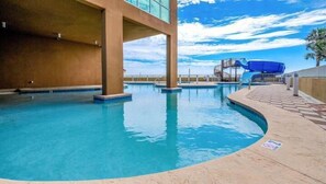 Ein Innenpool mit klarem, blauem Wasser, ein überdachter Bereich mit blauem Dach und ein gefliester Weg, der den Pool umgibt.
