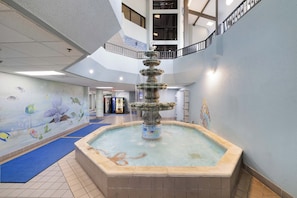 A multi-level indoor space with a central fountain, tiled flooring, and a mural with aquatic themes. - Phoenix V 1509 by Liquid Life (Orange Beach)