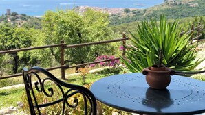 A round table with a potted plant, a metal chair, and a view of the sea and hills. - Casale Regina - Marina di Camerota (Marina di Camerota)