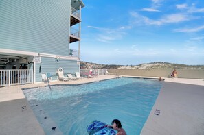 Ein Schwimmbecken mit Liegestühlen und ein Gebäude mit einem Balkon.