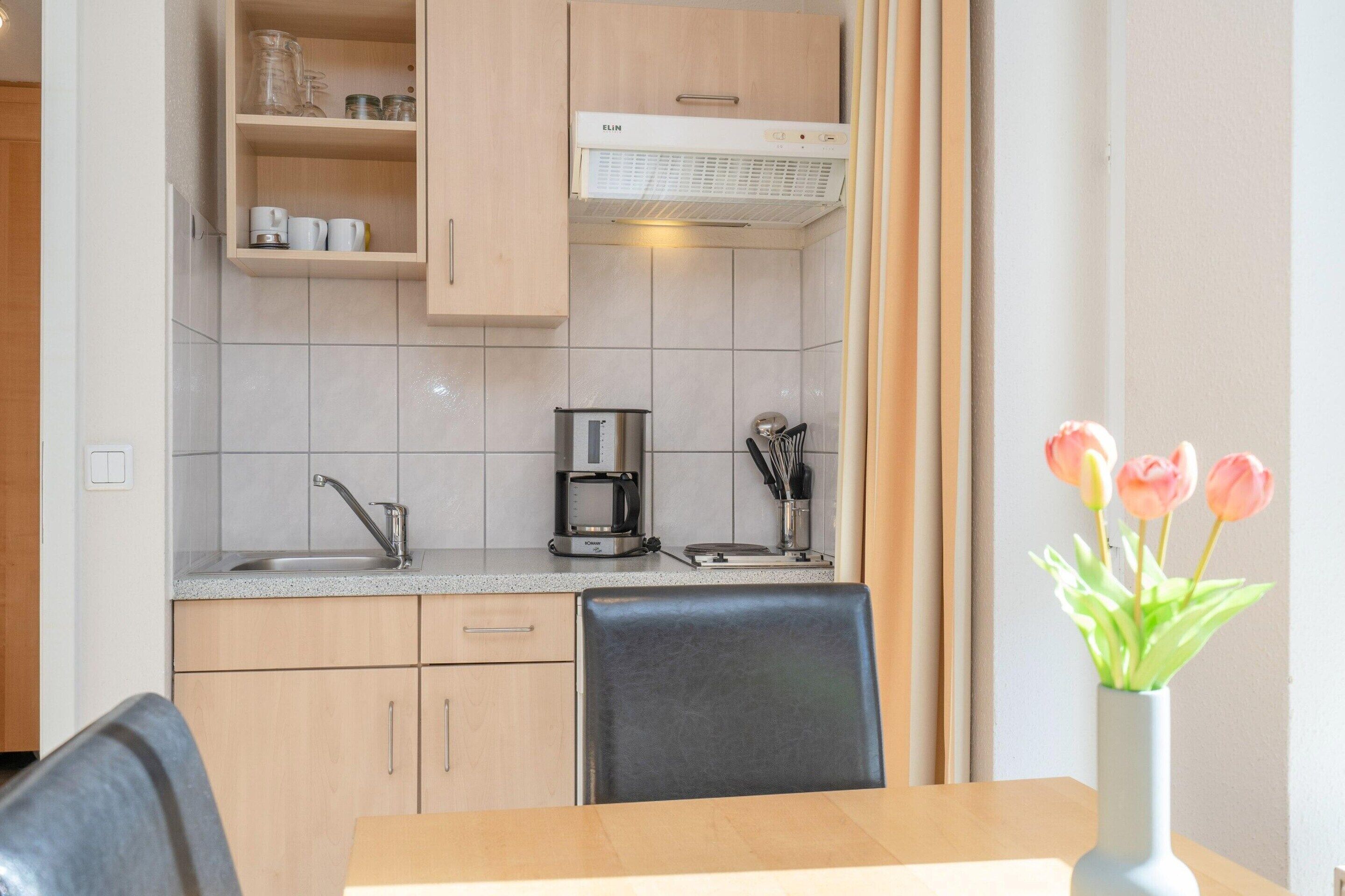 Een keuken met een koffiezetapparaat, een spoelbak en een kastje boven het aanrecht.
