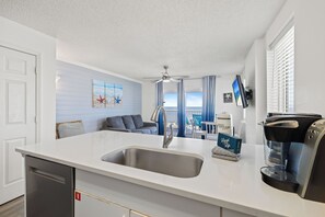 Eine moderne Küche mit integriertem Spülbecken, einer Kaffeemaschine und Meerblick durch das Fenster.