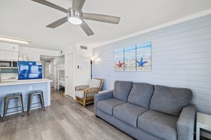 Eine moderne Küche mit einer Mikrowelle, einem blauen Kühlschrank und einer Bar mit Hockern.