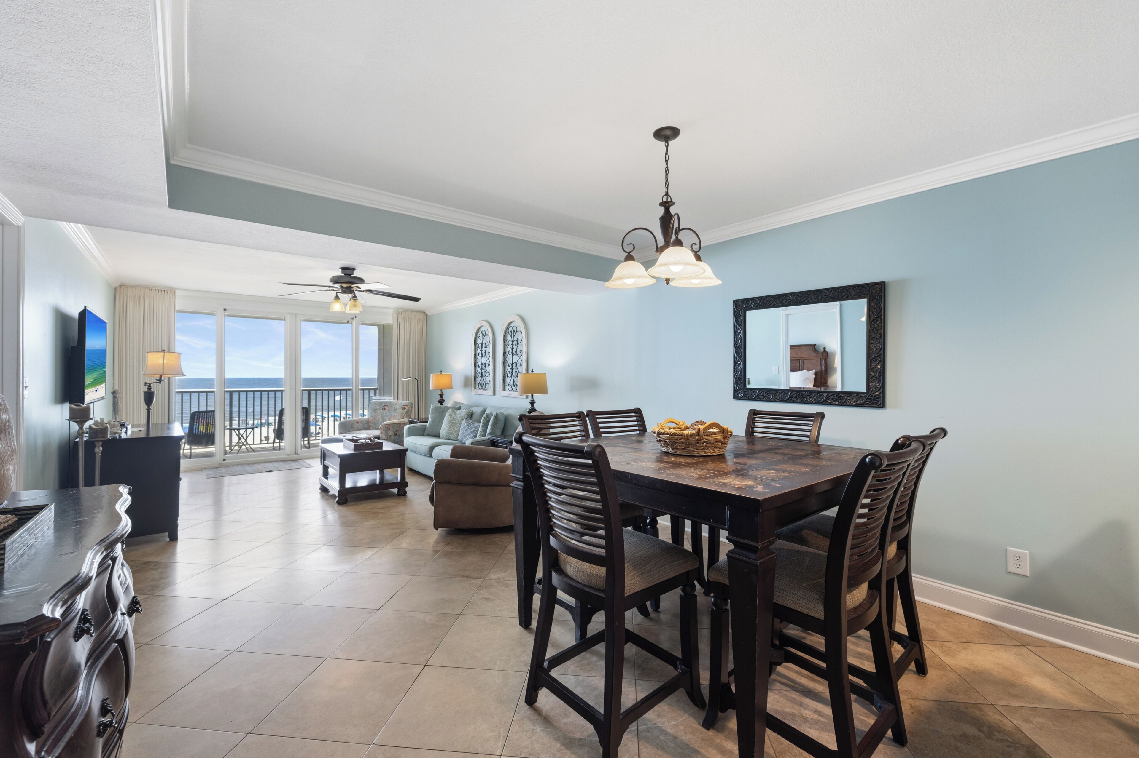 A spacious living area with a dining table, chairs, and a view of the ocean through large windows.
