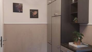Une cuisine avec des carreaux de couleur sombre, une porte blanche et deux tableaux encadrés accrochés au mur.