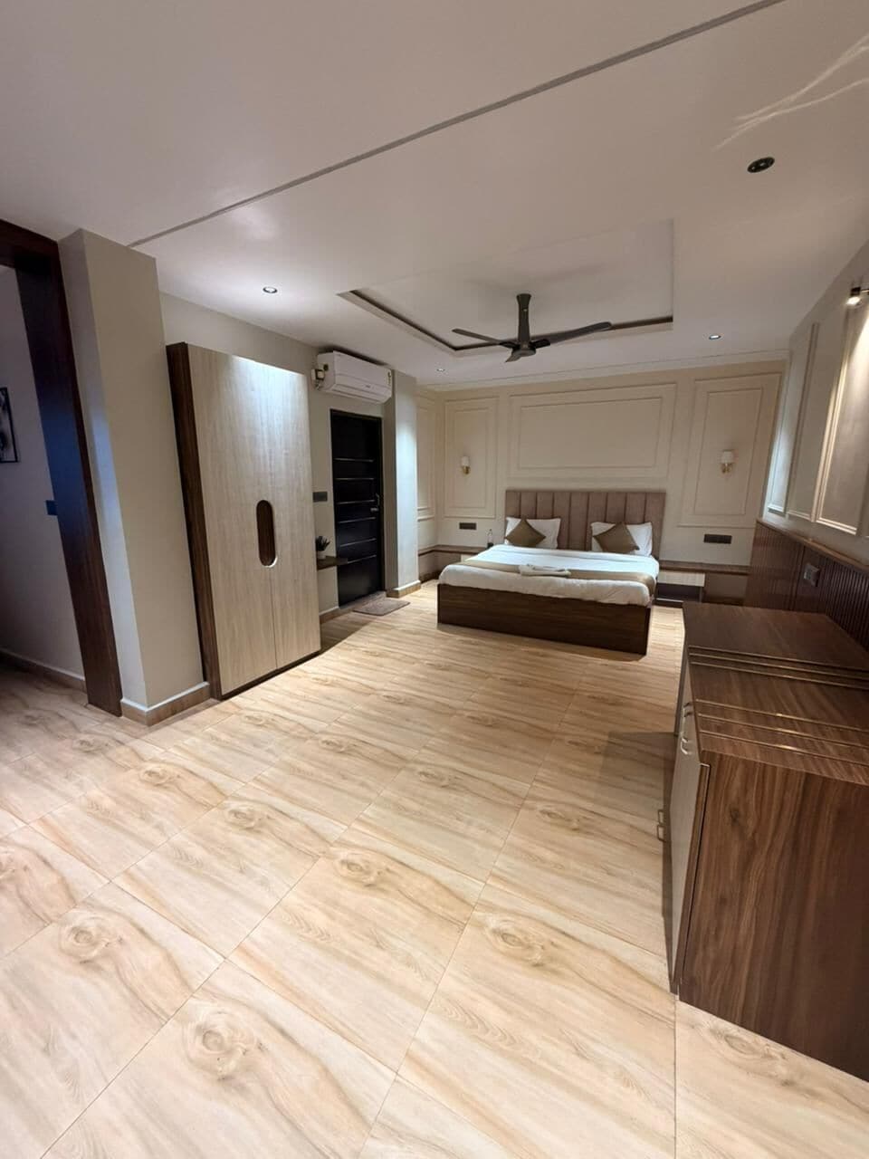Um quarto moderno com uma cama grande, um ventilador de teto e piso de madeira.