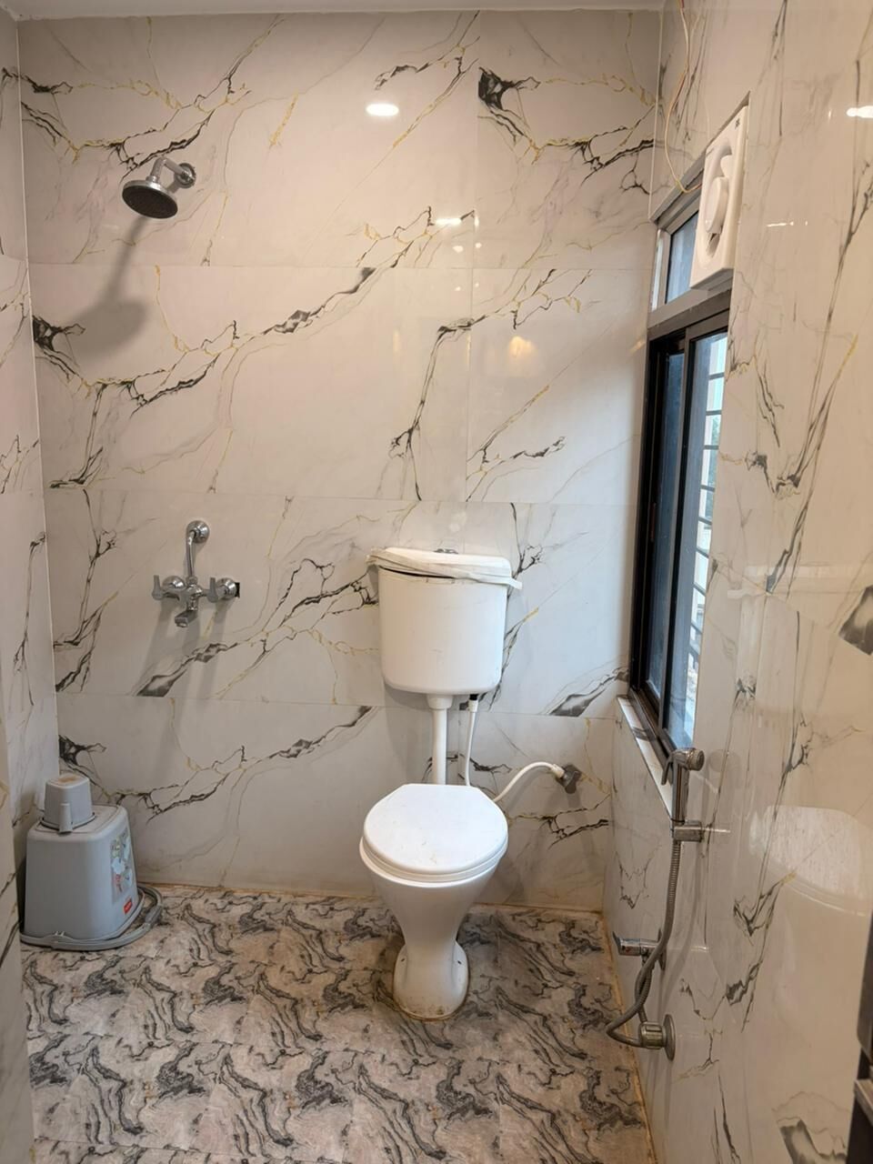 Ein Badezimmer mit Toilette, Dusche und Marmorwänden.