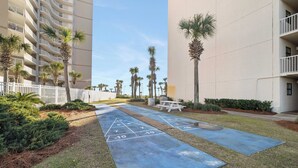 A courtyard with a shuffleboard court, palm trees, and a picnic table. - Seaside Beach & Racquet 4608 by Liquid Life (Orange Beach)