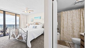Een slaapkamer met een bed, een plafondventilator, uitzicht op het strand en een badkamer met toilet en douchegordijn.