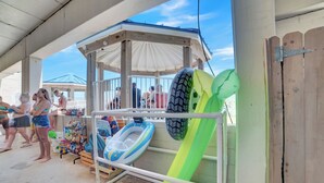 A covered outdoor area with a gazebo, inflatable water toys, and a wooden fence. - Sugar Beach 325 by Liquid Life (Orange Beach)