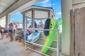 A covered outdoor area with a gazebo, inflatable water toys, and a wooden fence. - Sugar Beach 325 by Liquid Life (Orange Beach)