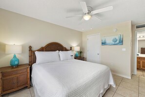 Ein Schlafzimmer mit einem Bett, Nachttischen, einem Deckenventilator, einem Gemälde und einer Tür.