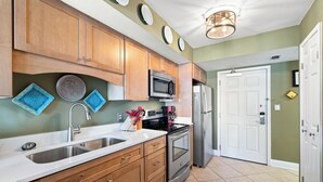 A kitchen with wooden cabinets, stainless steel appliances, and a white countertop. - Surfside Shores 1803 by Liquid Life (Gulf Shores)