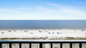 A beach with umbrellas and beach chairs, a fence, and a view of the ocean. - Surfside Shores 1803 by Liquid Life (Gulf Shores)