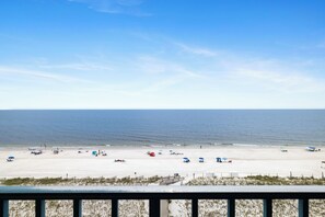 A beach with umbrellas and beach chairs, a fence, and a view of the ocean. - Surfside Shores 1803 by Liquid Life (Gulf Shores)