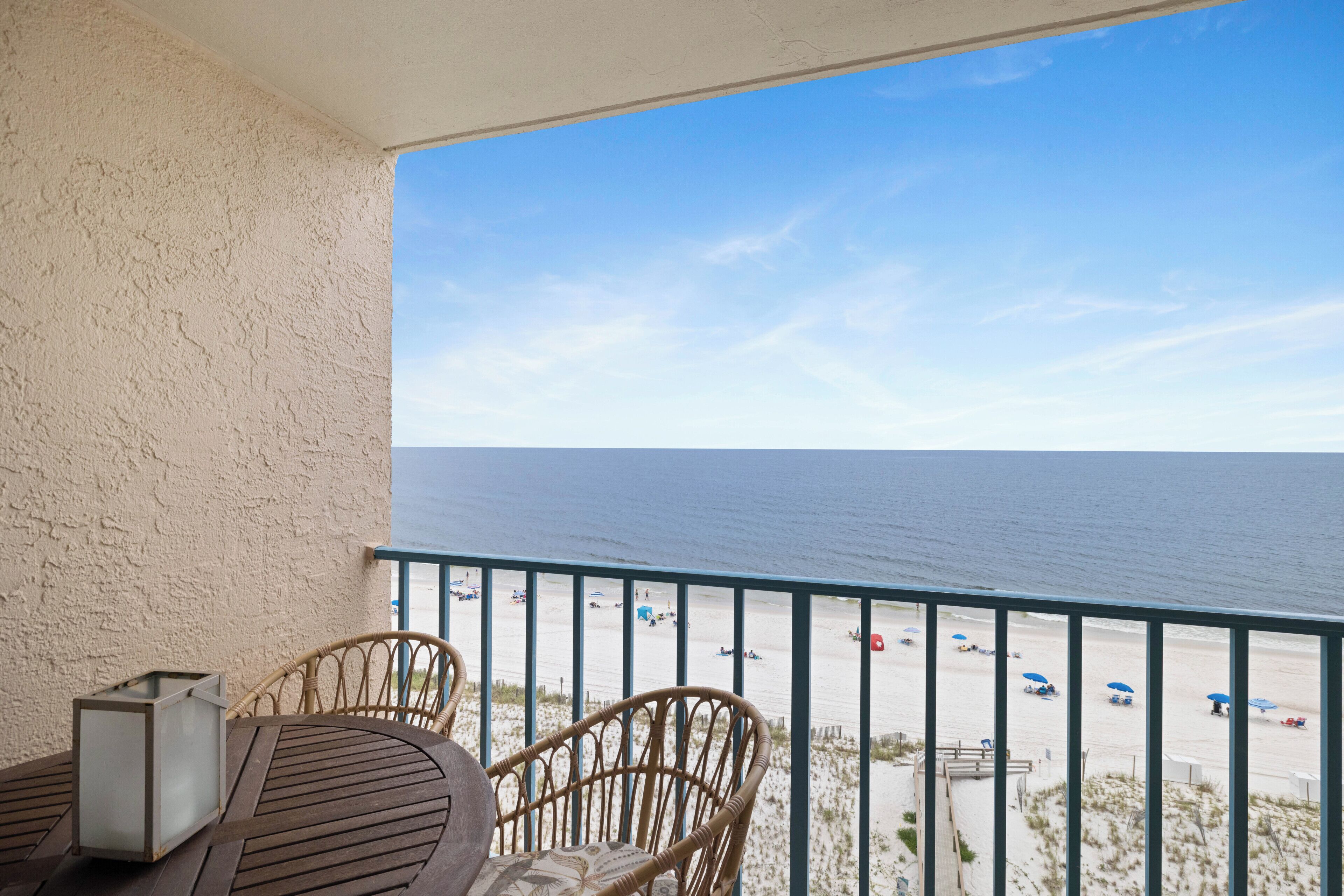 Ein Balkon mit Blick auf den Strand, Korbmöbel und ein Tisch.