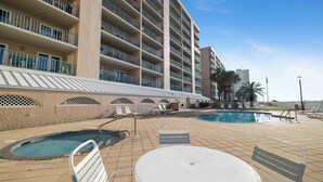 A hotel with multiple balconies, a swimming pool, and outdoor seating. - Surfside Shores 1803 by Liquid Life (Gulf Shores)