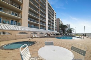 A hotel with multiple balconies, a swimming pool, and outdoor seating. - Surfside Shores 1803 by Liquid Life (Gulf Shores)