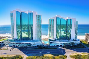 Ein modernes Hotel mit geschwungener Fassade, mehreren Etagen und einem Poolbereich.