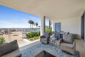 A balcony with wicker furniture, a pool, and a view of the beach. - Windward Pointe 103 by Liquid Life | Ground-Floor Unit (Orange Beach)