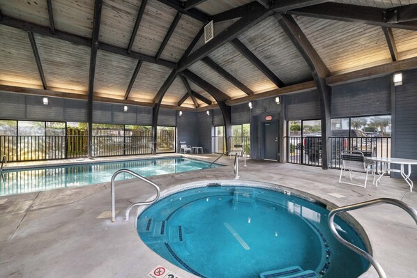 Una piscina interior con dos áreas separadas, barandillas metálicas y una estructura de techo cubierta.