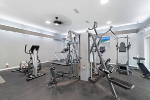 A gym with various exercise machines, a treadmill, and a ceiling fan. - Windward Pointe 103 by Liquid Life (Orange Beach)