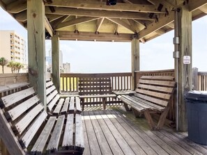 Eine Holzterrasse mit Bänken und einem Mülleimer.