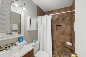 Ein Badezimmer mit Waschbecken, Spiegel, Toilette, Dusche und Handtuchhalter.