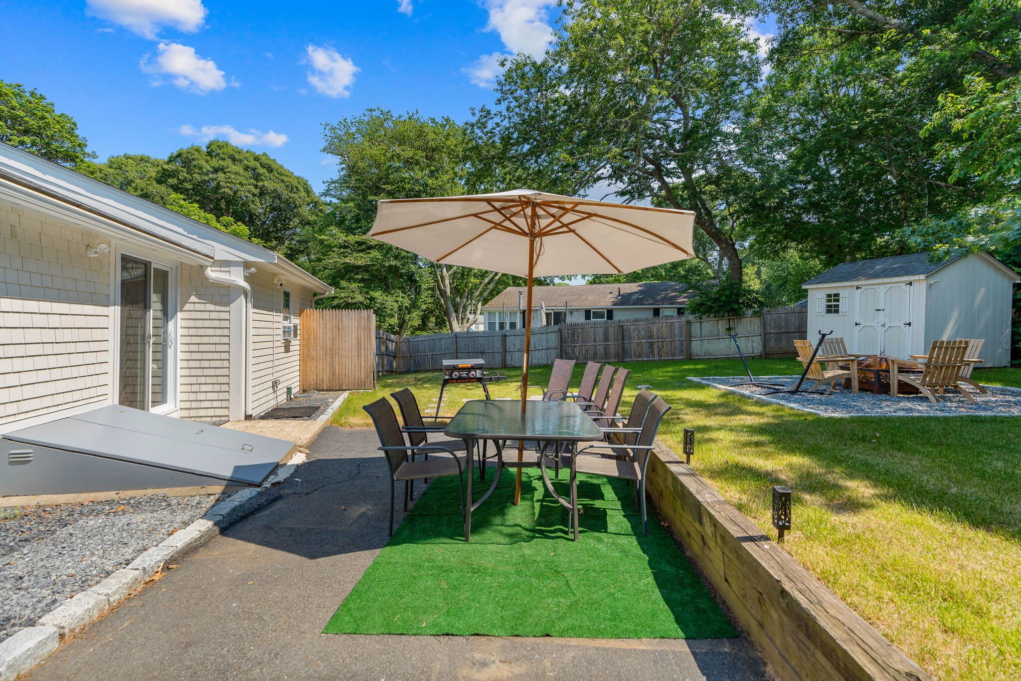 A backyard with a patio table, chairs, and an umbrella.