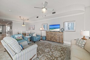 Ein Wohnzimmer mit einer Couch, Sesseln, einem Fernseher und Kunstwerken an den Wänden.